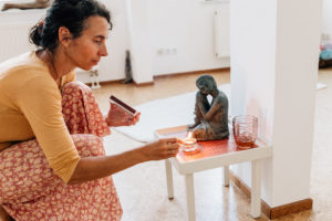 Die Yogalehrerin Maria Lichtenberg zündet in ihrem Yogaraum in Leipzig vor dem Beginn der Unterrichtsstunde eine Kerze vor der kleinen Statue eines schlafenden Buddha an.